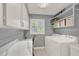 Neat laundry room with white cabinets, gray walls, a window and modern washer and dryer at 4309 Deepwater Ln, Tampa, FL 33615