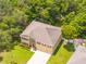 Aerial view of the two-story home surrounded by mature trees, green lawn, and a three car garage at 5147 Elwood Rd, Spring Hill, FL 34608