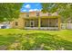 Backyard view of the house with a screened porch, green lawn, and white fence, offering privacy at 5147 Elwood Rd, Spring Hill, FL 34608