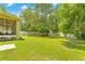 Lush backyard featuring a well-maintained lawn, mature trees, and a white fence, creating a serene outdoor space at 5147 Elwood Rd, Spring Hill, FL 34608