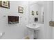 Stylish powder room featuring a pedestal sink, framed artwork and modern fixtures at 5147 Elwood Rd, Spring Hill, FL 34608