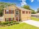 Two-story home with a three car garage, stone accents, red shutters and a red front door at 5147 Elwood Rd, Spring Hill, FL 34608