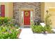 Close-up of the red front door framed by stone, plants and a decorative wreath at 5147 Elwood Rd, Spring Hill, FL 34608