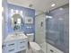 Bright bathroom with blue walls, glass-enclosed shower, and round mirror at 521 Pinellas Bayway S # 104, St Petersburg, FL 33715