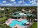 Aerial view of the community pool, showcasing its unique shape, lounge chairs, and surrounding tropical landscaping at 6400 Falcon Lair Dr, North Port, FL 34287