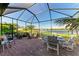 Outdoor patio seating area with lake views, lush landscaping, and a screen enclosure at 7115 Marsh View Ter, Bradenton, FL 34212