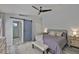 A modern bedroom with gray flooring, ceiling fan, accent rug, night stands, and a sliding barn door to the bathroom at 7609 Clair Wood Ct, Apollo Beach, FL 33572