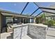 Outdoor screened-in patio featuring a stone bar, comfortable seating, and a view of the backyard and water at 7609 Clair Wood Ct, Apollo Beach, FL 33572