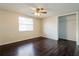 This bedroom includes neutral walls, a ceiling fan, a closet, and dark wood-look flooring at 7825 Bolam Ave, New Port Richey, FL 34653