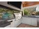 Modern outdoor kitchen featuring stainless steel appliances, black countertops, a grill, and an egg cooker at 1002 S Frankland Rd, Tampa, FL 33629
