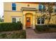 Inviting front entrance with an orange door, trimmed columns, and manicured landscaping, exudes classic comfort and style at 122 Coquina Bay Dr, St Petersburg, FL 33705