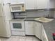 Kitchen features white appliances, white cabinets, and tile backsplash at 1308 Pine Ridge E Cir # E3, Tarpon Springs, FL 34688