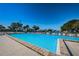 Large, inviting community pool with lounge chairs and umbrellas under a clear blue sky at 1308 Pine Ridge E Cir # E3, Tarpon Springs, FL 34688