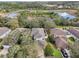 Aerial view of a home with a fenced backyard, mature trees, and a view of a pond at 15701 Greyrock Dr, Spring Hill, FL 34610