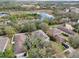 Aerial view of a home with a fenced backyard, mature trees, and a view of a pond at 15701 Greyrock Dr, Spring Hill, FL 34610