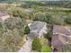 Aerial view of a home with a fenced backyard, mature trees, and a view of a pond at 15701 Greyrock Dr, Spring Hill, FL 34610