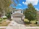 Two-story home with a two-car garage, well-manicured lawn, and mature trees at 15701 Greyrock Dr, Spring Hill, FL 34610
