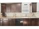 Kitchen features dark wood cabinetry, granite countertops, stainless steel dishwasher, and tile backsplash at 15701 Greyrock Dr, Spring Hill, FL 34610
