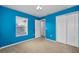 Bright bedroom with vivid blue walls, a window with blinds, and a closet with sliding doors at 19609 Timberbluff Dr, Land O Lakes, FL 34638