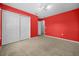Cozy bedroom with red walls, neutral carpet, overhead lighting, and a double closet at 19609 Timberbluff Dr, Land O Lakes, FL 34638