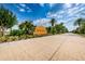 The 'Tierra del Sol' community entrance with lush landscaping, palm trees, and a paved road at 19609 Timberbluff Dr, Land O Lakes, FL 34638