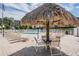 Community pool with tiki umbrella, lounge chairs, and tables at 2700 Cove Cay Dr # 4-B, Clearwater, FL 33760