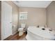 Bathroom with a corner tub, toilet, wood-look flooring, and a window for natural light at 3307 Fox Ridge Blvd, Wesley Chapel, FL 33543