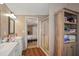 Bathroom with dual vanities, a glass-enclosed shower, wood-look floor, and access to bedroom at 3307 Fox Ridge Blvd, Wesley Chapel, FL 33543