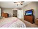 Comfortable bedroom with a ceiling fan, wooden dresser, and television with a beach scene at 3307 Fox Ridge Blvd, Wesley Chapel, FL 33543