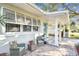 Inviting front porch with cozy seating area, brick flooring, and a turquoise front door at 349 Shirley Ave, Belleair, FL 33756