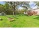 A spacious backyard has a fire pit and mature trees offering shade and a relaxing outdoor space at 36246 Peak St, Zephyrhills, FL 33541