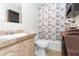 Well-lit bathroom with vanity, toilet, and shower with decorative curtain, complemented by storage shelves at 36246 Peak St, Zephyrhills, FL 33541