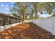 A spacious backyard features a screened lanai, tall shade trees, mulch, and a privacy fence at 3907 Elkcam Se Blvd, St Petersburg, FL 33705