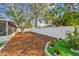 Landscaped backyard featuring a screened lanai, white vinyl fence, and decorative mulch at 3907 Elkcam Se Blvd, St Petersburg, FL 33705