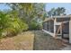 View of the backyard with the screened in porch attached to the house surrounded by mature landscaping at 3915 N Ola Ave, Tampa, FL 33603