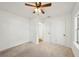 Neutral carpeted bedroom featuring a ceiling fan, white walls, closet, and door to another room at 3915 N Ola Ave, Tampa, FL 33603