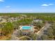 Aerial view of the community pool featuring a bath house, play ground, and lots of green trees at 4421 Larkenheath Dr, Spring Hill, FL 34609