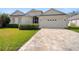 A spacious two-car garage with an attractive multi-hued brick driveway and manicured lawn showcases lovely curb appeal at 4421 Larkenheath Dr, Spring Hill, FL 34609