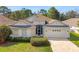 Charming single-story home with a well-manicured lawn, complemented by lush landscaping and a welcoming two-car garage at 4421 Larkenheath Dr, Spring Hill, FL 34609