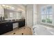 Elegant bathroom featuring a soaking tub, double vanity, and natural light from the window with shutters at 5229 Brighton Shore Dr, Apollo Beach, FL 33572