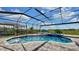 In-ground pool inside an enclosed pool cage with spa, chairs and decorative greenery at 5317 Del Coronado Dr, Apollo Beach, FL 33572