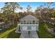 Aerial view of a raised beach house with a two-car garage and a balcony surrounded by lush landscaping at 6841 Oelsner St, New Port Richey, FL 34652