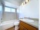 Bathroom features a bathtub-shower combination, neutral tile and lighting, and a vanity with wooden cabinets at 8600 Berkley Dr, Hudson, FL 34667