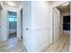 Hallway with wood-look floors and white walls leads to bathroom and back door at 8600 Berkley Dr, Hudson, FL 34667