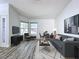 Staged living room with stylish decor, wood-look flooring, and a large TV at 8600 Berkley Dr, Hudson, FL 34667