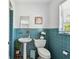 Bright bathroom featuring blue tile, pedestal sink, window, toilet, and decorative art at 11124 Corlett Rd, Riverview, FL 33578