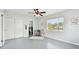 Bedroom with gray floors, bathroom access, bright windows, and a ceiling fan at 11124 Corlett Rd, Riverview, FL 33578