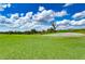 Expansive golf course view with lush green grass, mature trees, and a bright blue sky with fluffy white clouds at 1168 Emerald Hill Way, Valrico, FL 33594