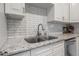 Well-lit kitchen sink area featuring stainless steel appliances, granite counters and subway tile backsplash at 1209 E Idlewild Ave, Tampa, FL 33604