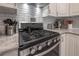 Well-equipped kitchen featuring a stainless steel stove and oven, white cabinets, and subway tile backsplash at 1209 E Idlewild Ave, Tampa, FL 33604